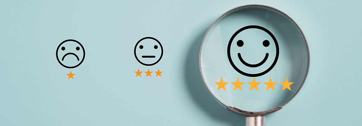 Sad face with one star, neutral face with three stars and a happy face with 5 stars under a magnifying glass